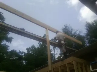 Carpenter setting a ridge beam over a new addition frame — Ice Dam Removal by Roofing Brothers in Genesee