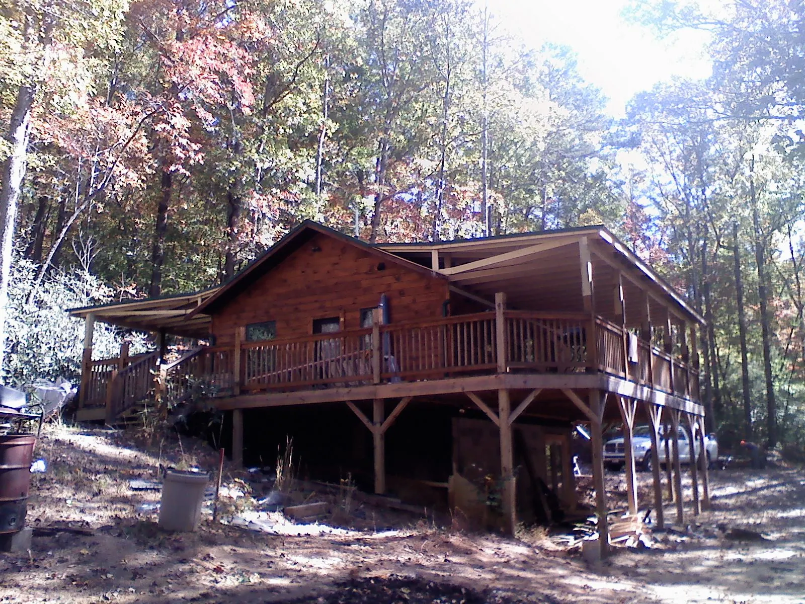 Log cabin with a wraparound porch and metal roof in the fall in Genesee