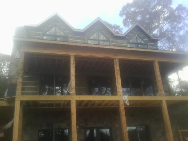 Dormers and porch framing on a large log home under construction — Roof Coating work by our crew in Genesee